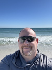 a man wearing sunglasses taking a selfie on the beach
